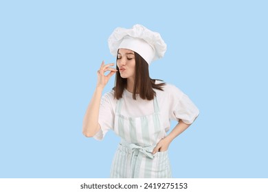 Young female chef in uniform making delicious gesture on blue background - Powered by Shutterstock