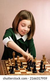 Young Female Chess Player Has Cunning Plan. Child Girl Find Good Move In Chess Game. Schoolgirl Plays At Chessboard In Green Dress. Middlegame.