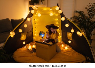 Young female child using magnifying glass to explore earth globe in a home made livingroom tent with light balls. - Powered by Shutterstock