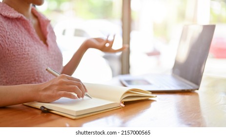 A young female college student doing her work assignment and researching the informations on the internet via laptop. rear view, cropped image - Shutterstock ID 2157000565
