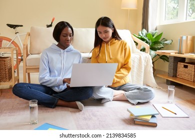 Young female college students watching educational video on laptop when working on project together