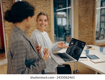Young female computer programmers is coding at laptop while standing in coworking 