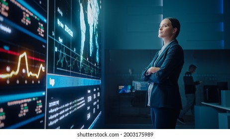 Young Female Computer Science Engineer Looking At Big Screen Display Showing Global Map With Data Points. Telecommunications Technology Company System Control And Monitoring Room With Servers.