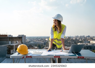 Young female construction specialist engineer reviewing blueprints at construction site - Powered by Shutterstock