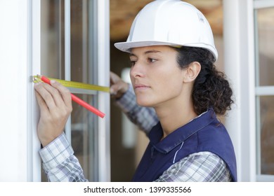 young female construction worker measuring window