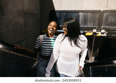 Young female couple getting off the the metro throught the escalators and reaching for the first time in a new city. Their faces reflect excitement and happiness as they begin their trip. - Powered by Shutterstock