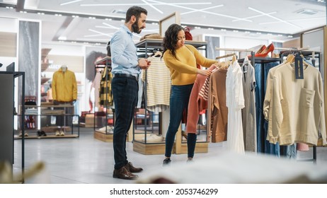 Young Female Customer Shopping In Clothing Store, Retail Sales Associate Helps With Advice. Diverse People In Fashionable Shop, Choosing Stylish Clothes, Colorful Brand With Sustainable Designs