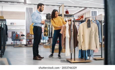 Young Female Customer Shopping In Clothing Store, Retail Sales Associate Helps With Advice. Diverse People In Fashionable Shop, Choosing Stylish Clothes, Colorful Brand With Sustainable Designs