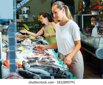 Young Female Customers Choosing Fresh Raw Seafoods From Large Assortment Of Fish Store