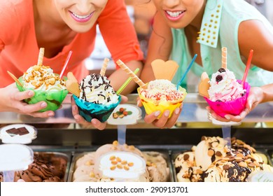 Young female customers or friends with sorts of ice cream for cornets and cones and sundaes in parlor