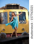 Young female dancer in front of train in turquoise dress