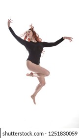 young female dancer/ model in dark leotard dancing and jumping with frozen movement. On white background in the studio.