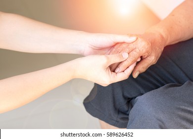 Young Female Daughter Hands Holding Elderly Aging Old Grandmother Hand To Support/comfort Her With Lens Flair Effect. World Elder Abuse Awareness Day, Disability Caregiver Healthcare Concept