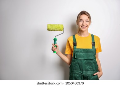 Young Female Decorator With Paint Roller On White Background