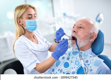 A Young Female Dentist Controls Health Of The Tooth Of An Older Patient