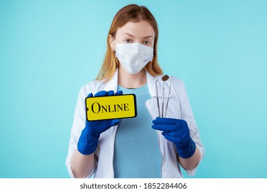 Young Female Dentist In Mask And Medical Coat Holding Instruments And Phone. Appointment Online Cocnept.