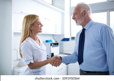 Young Female Dentist And Patient Are Shaking Hands In A Dental Office