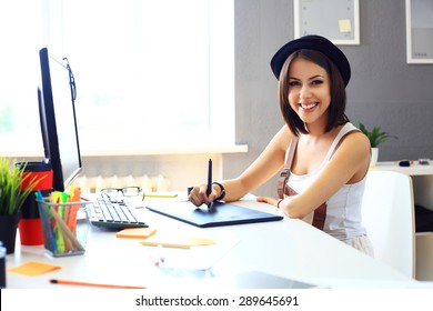 Young female designer using graphics tablet while working with computer - Powered by Shutterstock