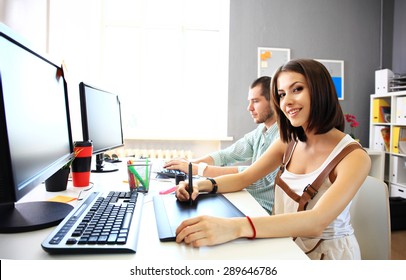 Young female designer using graphics tablet while working with computer