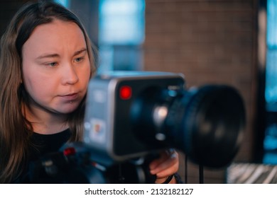 A Young Female Director Of Photography At Work Behind A Movie Camera On A Film Set For A Movie, Commercial Or Broadcast. Modern Photography Technology.