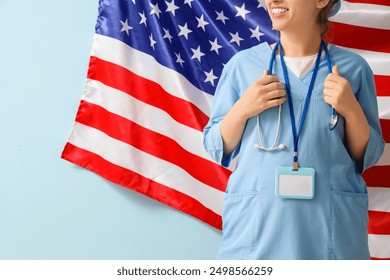 Young female doctor with blank name tag and USA flag on blue background - Powered by Shutterstock