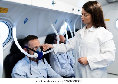 Young Female Doctor Checking Mask Of A Patient During Hyperbaric Oxygen Therapy At Clinic. 