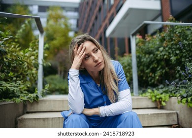 Young female doctor feeling overwhelmed at work, sitting on stairs, looking at phone. Healthcare workers having stressful job, feeling exhausted. Burnout syndrome for doctors and nurses. - Powered by Shutterstock