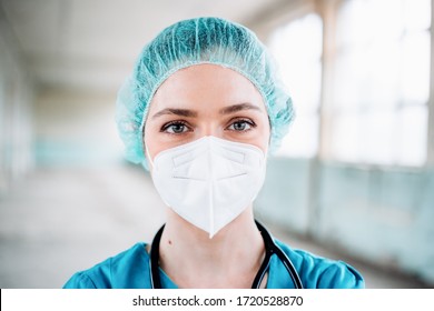 Young Female Doctor In A Green Uniform With Surgical Cap And Protection Mask, Close Up Portrait, Horizontal Background. Prevention Of Covid-19. 