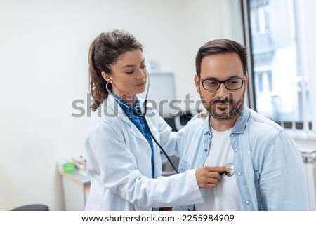 Young female doctor listen to male patient heart chest with stethoscope at clinic meeting. Woman GP checkup examine man client with phonendoscope. healthcare concept.