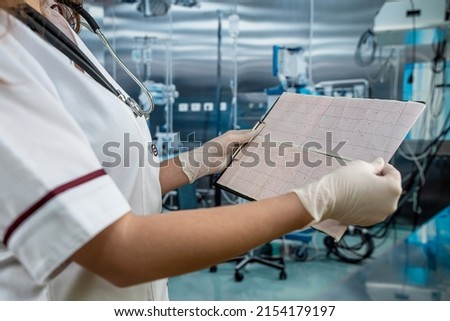 Young female doctor looks at the cardiogram of the heart to patient at operating room on hospital. Cardio Therapist