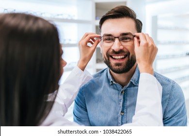 Young female doctor ophthalmologist is helping handsome man to choose the most appropriate eyeglasses. Doctor and patient in modern ophthalmology clinic - Shutterstock ID 1038422065