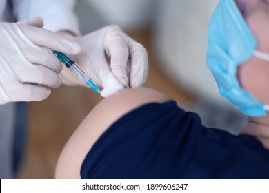 Young Female Doctor In Protective Mask Injecting Or Prepairing For Injecting Vaccine Against Coronavirus Or Ncov 19 Or Covid Into Patient's Arm