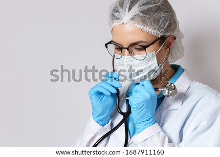 Young female doctor pulmonologist with a stethoscope on gray background