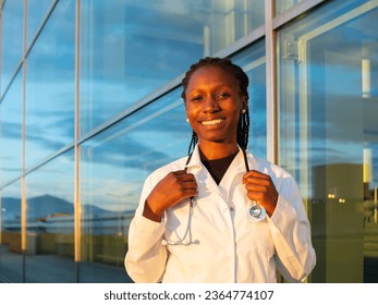 Young female doctor putting a stethoscope on her neck in front of a hospital while smiling Looking at camera - Shutterstock ID 2364774107