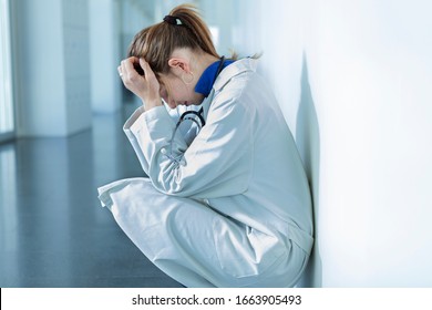 Young Female Doctor Sitting On The Floor Of A Hospital Corridor In Sad Or Tired Attitude