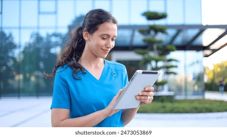 Young female doctor standing in front of her medical clinic and using a digital tablet - Powered by Shutterstock