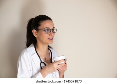 Young Female Doctor Taking A Break. Drinking Coffee And Smalltalk. Selective Focus Face.