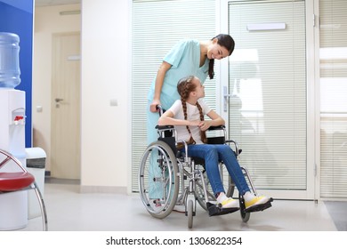 Young female doctor taking care of little girl in wheelchair indoors - Powered by Shutterstock