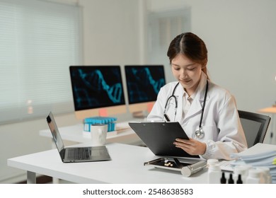 Young female doctor wearing lab coat and stethoscope is writing medical report about dna structure on clipboard while sitting at desk in modern clinic - Powered by Shutterstock