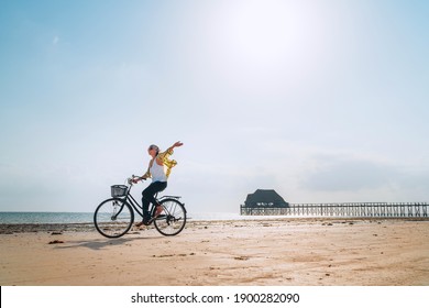 Young female dressed light summer clothes joyfully threw up her hand riding old vintage bicycle with front basket on the low tide ocean white sand coast on Kiwengwa beach on Zanzibar island, Tanzania. - Powered by Shutterstock