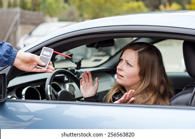 Young Female Driver Arguing With A Police Officer During Test For Alcohol Content With Breathalyzer, She Is Angry And Not Willing To Cooperate With Police Officer