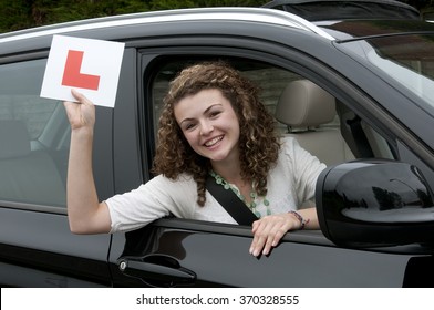 Young female driver holding L learner plate celebrating a pass rating