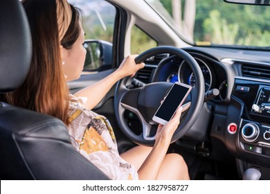 Young Female Driver Holding  A Smart Phone With Copy Space While Driving, Indicating Negligence