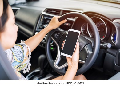 Young Female Driver Holding  A Smart Phone With Copy Space While Driving, Indicating Negligence