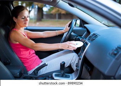 Young Female Driver Playing Music In The Car (changing CDs)