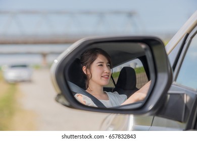 young female driver is reflected in a car side mirror. - Powered by Shutterstock