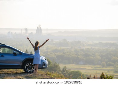 Young female driver resting near her car enjoying warm summer evening. Travel and getaway concept.