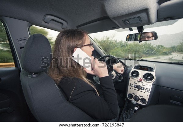 Young\
female driver using cellphone while driving a\
car