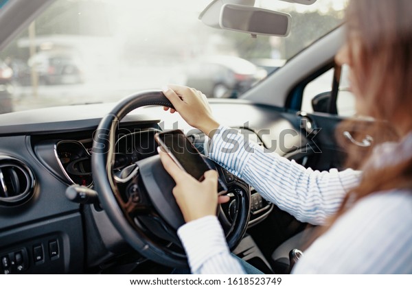 Young female driver using touch screen smartphone.\
Young female driver using touch screen smartphone and gps\
navigation in a car. Side View Of Young Woman Using Mobile Phone\
While Driving Car