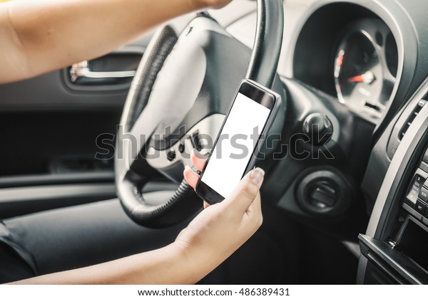 Young female driver using touch screen smartphone\
and gps navigation in a\
car.